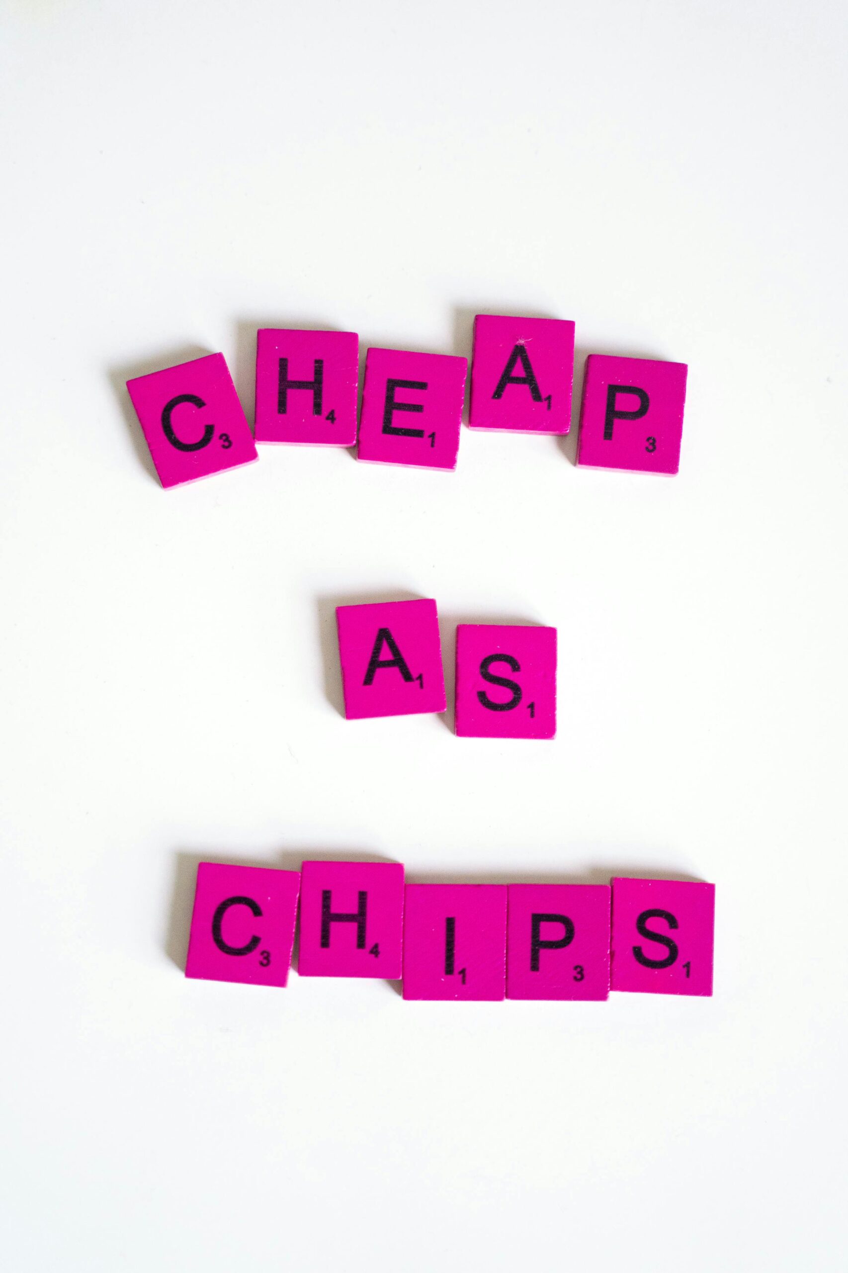 Colorful Scrabble tiles on white background spelling 'Cheap as Chips'